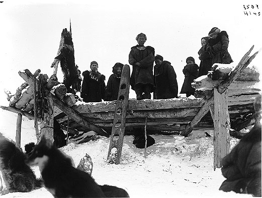 Koryaks standing on the roof of a winter house.